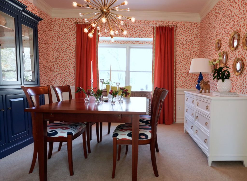 Bold dining room design featuring coral animal print wallaper and blue fuishings
