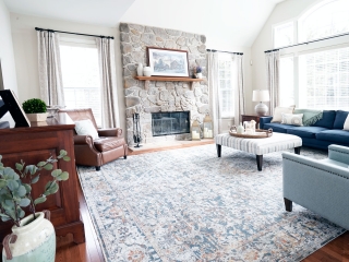 family room design in Phoenixville PA with stone fireplace, wood floating mantle, hardwood floors, navy sofa, fabric ottoman