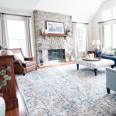 family room design in Phoenixville PA with stone fireplace, wood floating mantle, hardwood floors, navy sofa, fabric ottoman