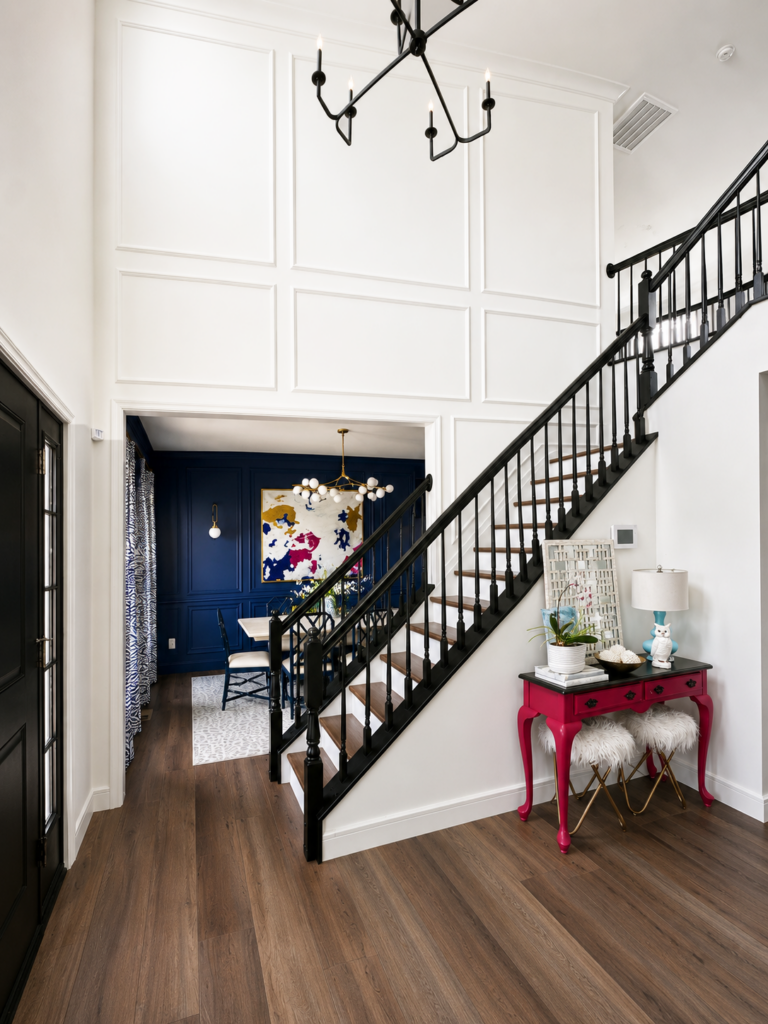 Foyer1 Two-story foyer with white wall molding, black staircase, warm wood floors and view into a navy dining room in Chester County PA