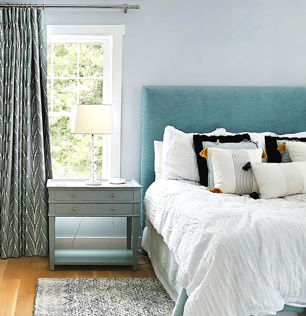 Bedroom design featuring custom upholstered headboard and window treatments