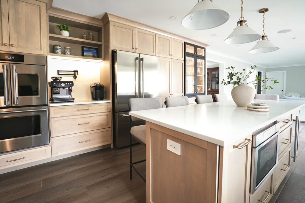 Kitchen appliance wall with built-in ovens, refrigerator, custom pantry and illuminated cabinetry.